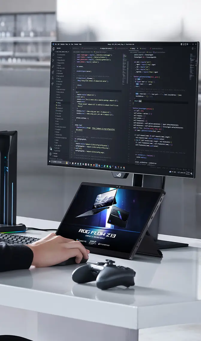 A man is seated at a desk with a keyboard, mouse, and the Flow Z13, actively coding on an external monitor.