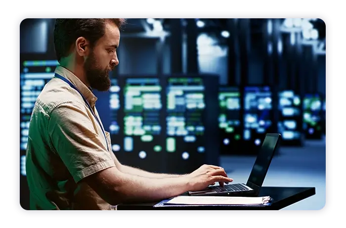 A man is seated at a computer in a data center monitoring center