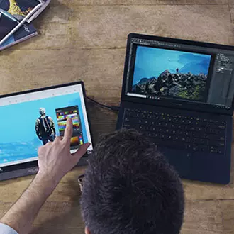 A man is working on a laptop with ASUS portable monitor